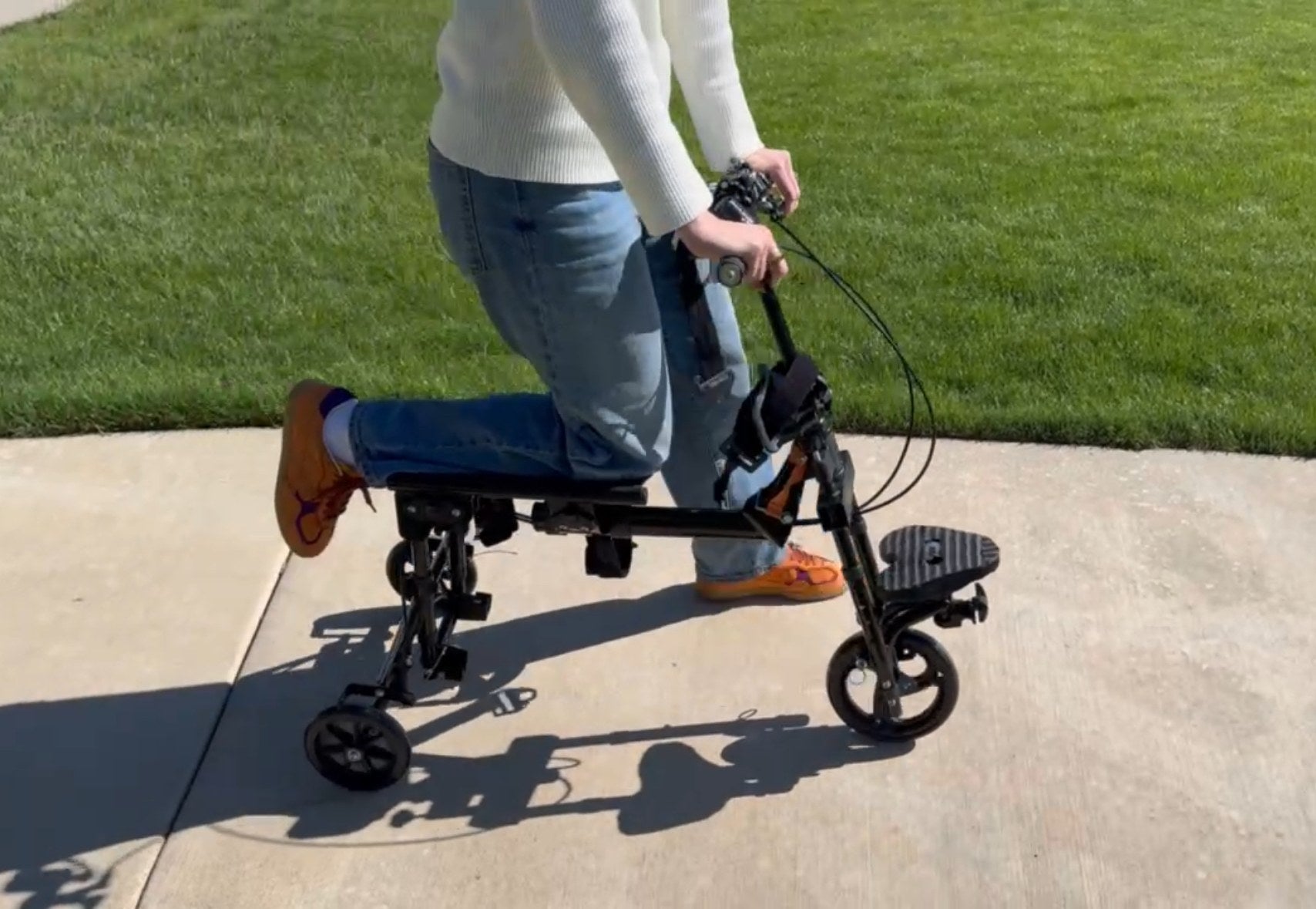 Person riding the EaziStep hybrid scooter-crutch on a sidewalk